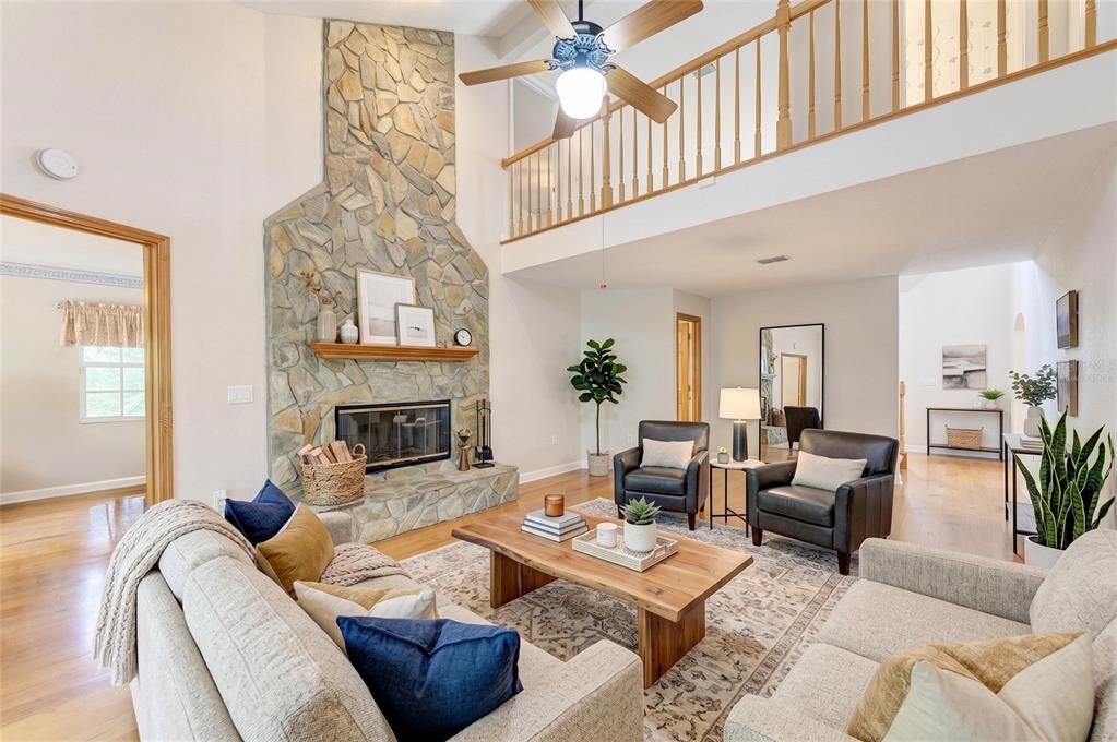 A living room features a stone fireplace, vaulted ceilings, a wooden coffee table, and furniture — 518 129TH STREET NE, BRADENTON, FL