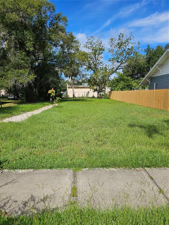 A covered front porch features a blue door, outdoor seating, and a patterned area rug — 2301 HIGHLAND STREET S, ST PETERSBURG, FL