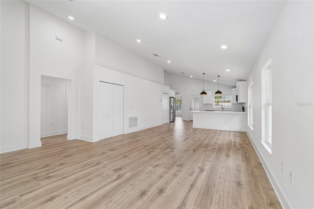 An open-concept living area features light wood-look flooring, white walls, and a kitchen with island — 2301 HIGHLAND STREET S, ST PETERSBURG, FL