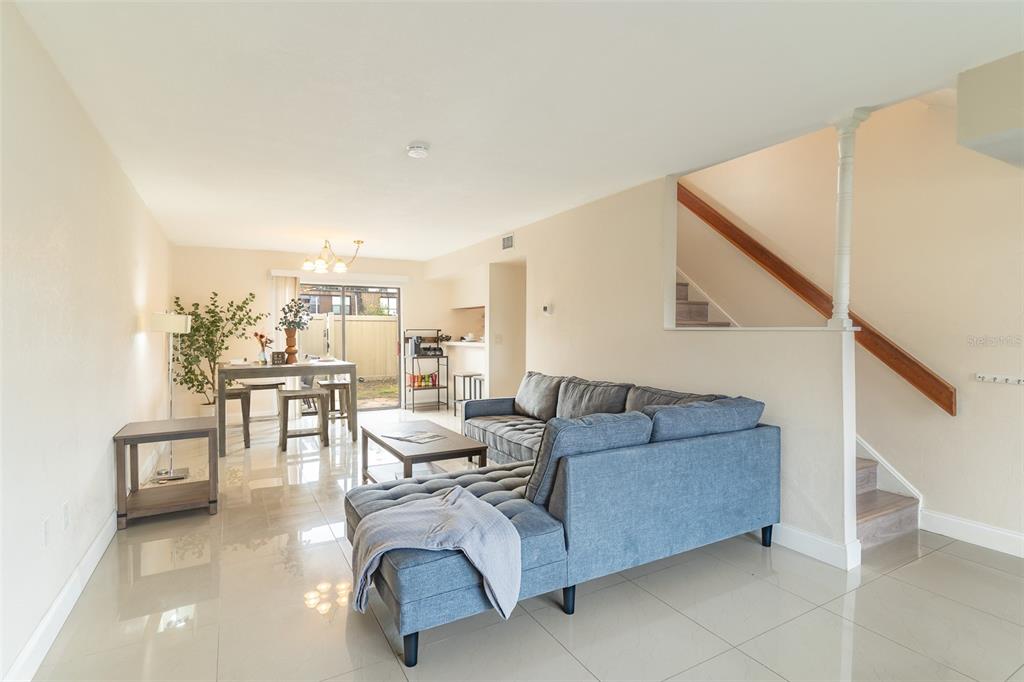 A living room and dining area with tile floors, a blue sectional, and a staircase — 1836 N CRYSTAL LAKE DRIVE UNIT 104, LAKELAND, FL