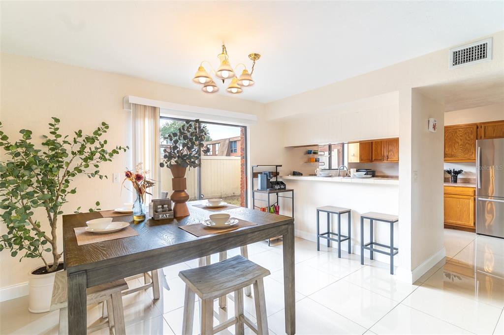 A dining area with a wooden table, tile floors, and an adjacent kitchen with bar seating — 1836 N CRYSTAL LAKE DRIVE UNIT 104, LAKELAND, FL