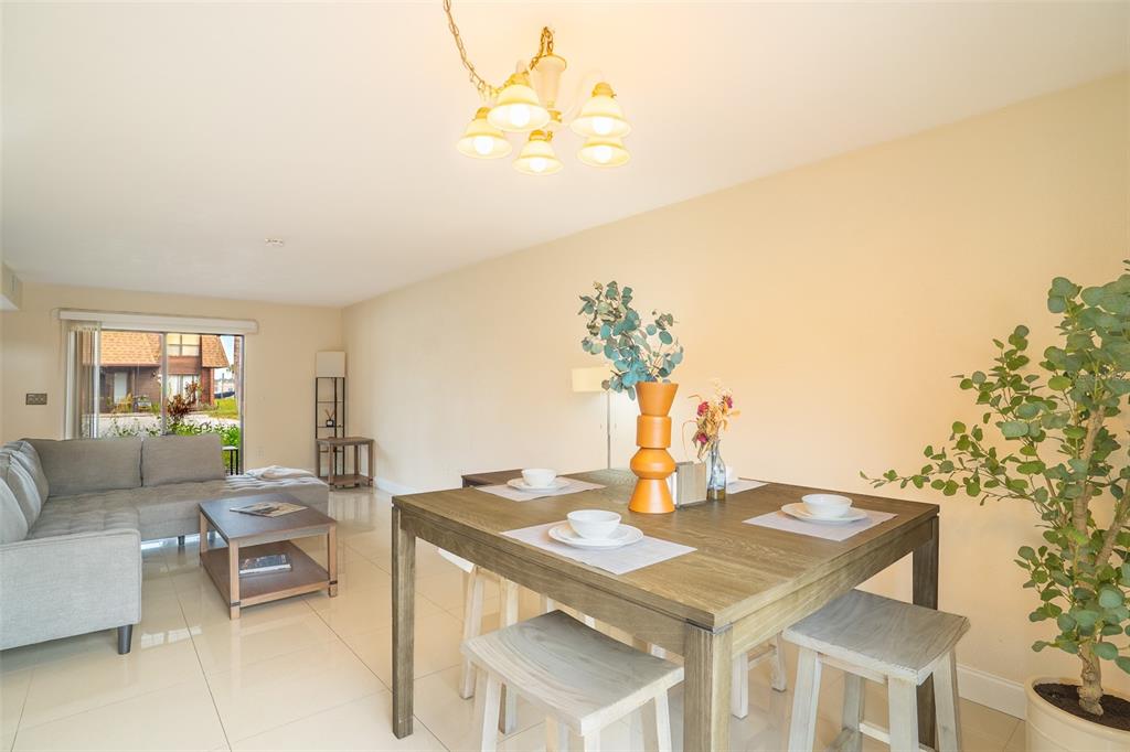 A dining area with a wooden table and stools sits adjacent to a living room — 1836 N CRYSTAL LAKE DRIVE UNIT 104, LAKELAND, FL