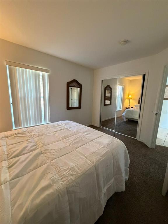 A bedroom features a bed, a window with vertical blinds, and mirrored closet doors — 2714 CLUB CORTILE CIRCLE, KISSIMMEE, FL