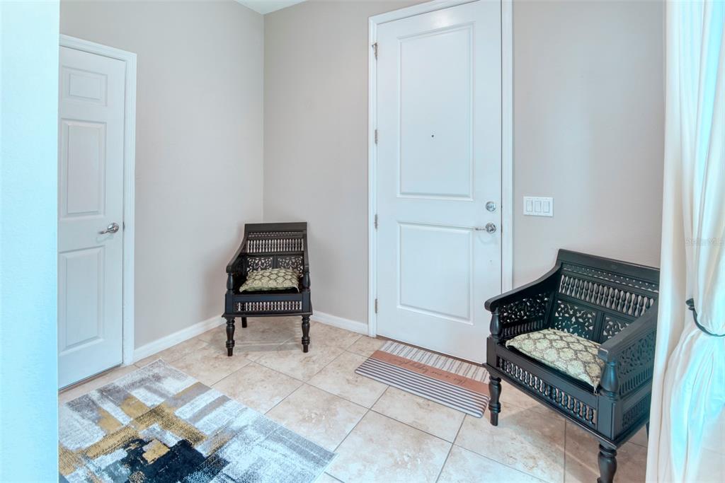 An entryway features tile flooring, two dark wooden chairs, and a white front door — 1390 HARBOR RIDGE DRIVE, KISSIMMEE, FL