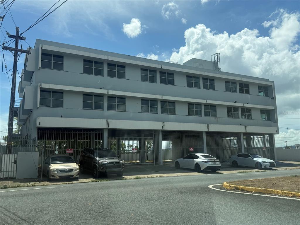A three-story gray commercial building with a ground-level parking area and metal security gates — 174 DR. AGUSTIN STAHL, BAYAMON, PR