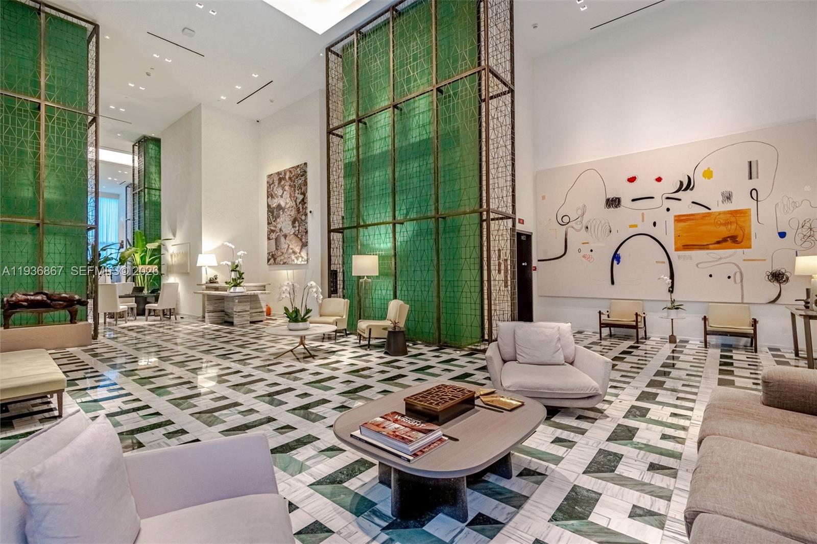 A spacious, high-ceilinged lobby features green geometric screens, marble floors, and modern lounge furniture — 801 S Miami Ave # 2405, Miami FL 33130, MIAMI, FL
