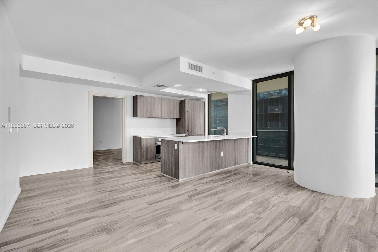 An open-concept kitchen features wood-grain cabinetry, white countertops, and light-colored wood-look flooring — 801 S Miami Ave # 2405, Miami FL 33130, MIAMI, FL
