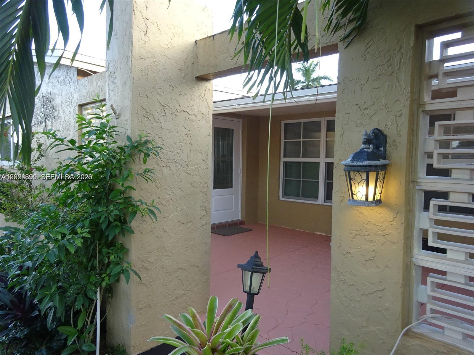 A covered entryway features a red concrete porch, a white door, and two outdoor lanterns — 9240 SW 56th St # 0, Cooper City FL 33328, COOPER CITY, FL