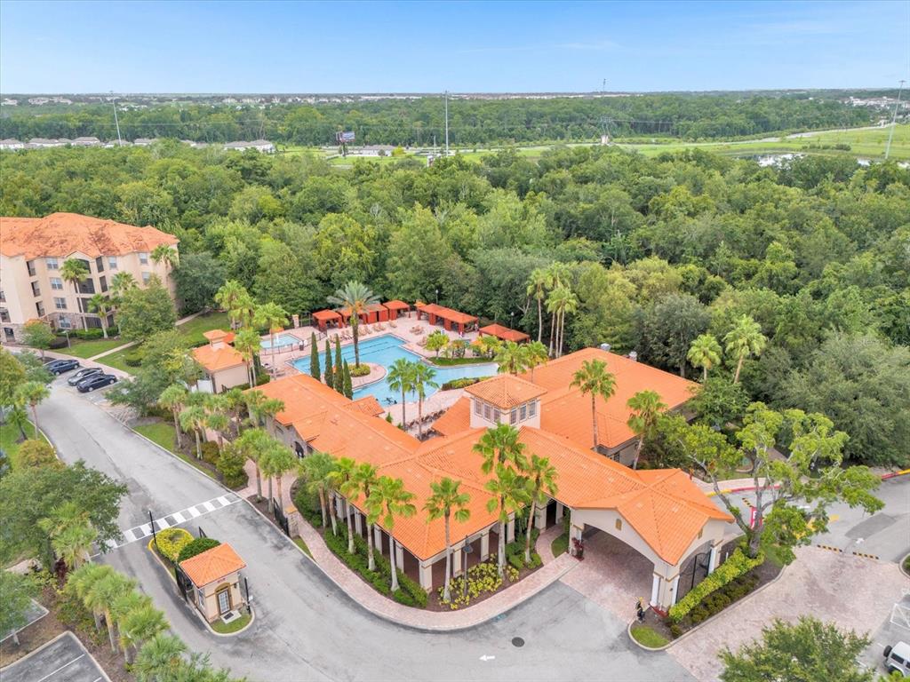 An aerial view shows a community clubhouse with a swimming pool and surrounding lush trees — 1351 TUSCAN TERRACE UNIT 8101, DAVENPORT, FL