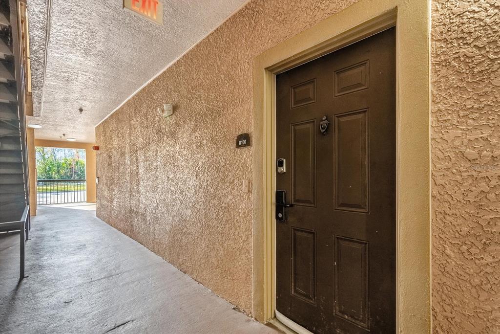 A dark brown door with a smart lock is set into a textured beige wall — 1351 TUSCAN TERRACE UNIT 8101, DAVENPORT, FL