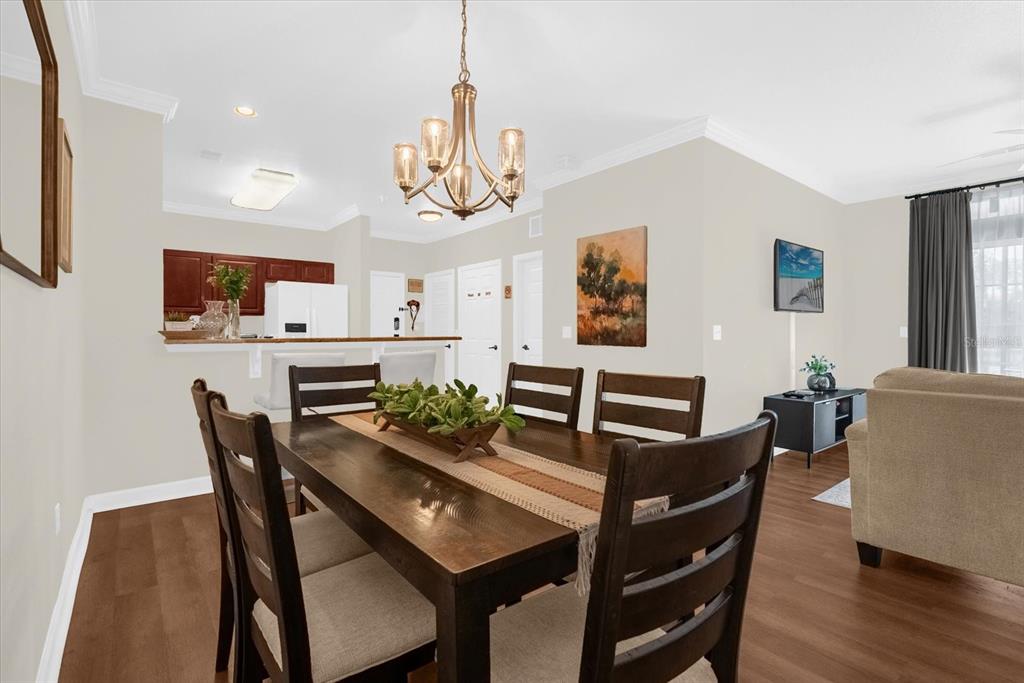 A dining room with a wooden table and chairs sits in front of an open kitchen — 1351 TUSCAN TERRACE UNIT 8101, DAVENPORT, FL
