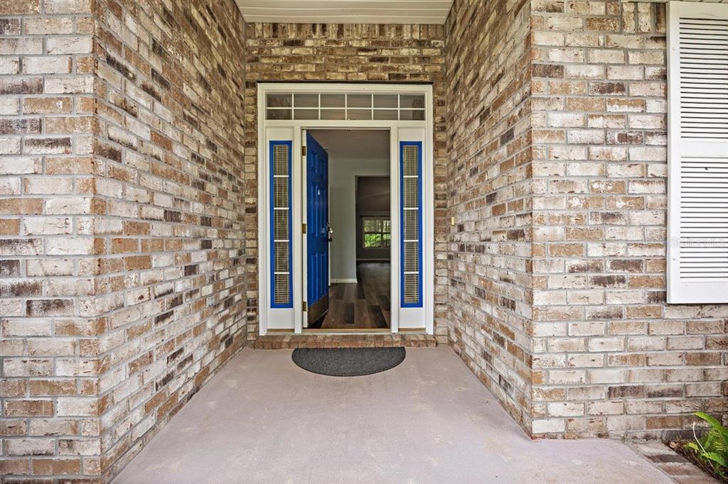 A brick-front entryway features a blue front door with sidelights and a transom window — 54 SELMA TRAIL, PALM COAST, FL