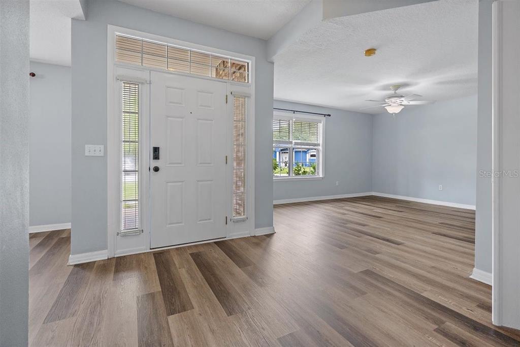 An entryway with light gray walls and wood-look flooring leads into an open living area — 54 SELMA TRAIL, PALM COAST, FL
