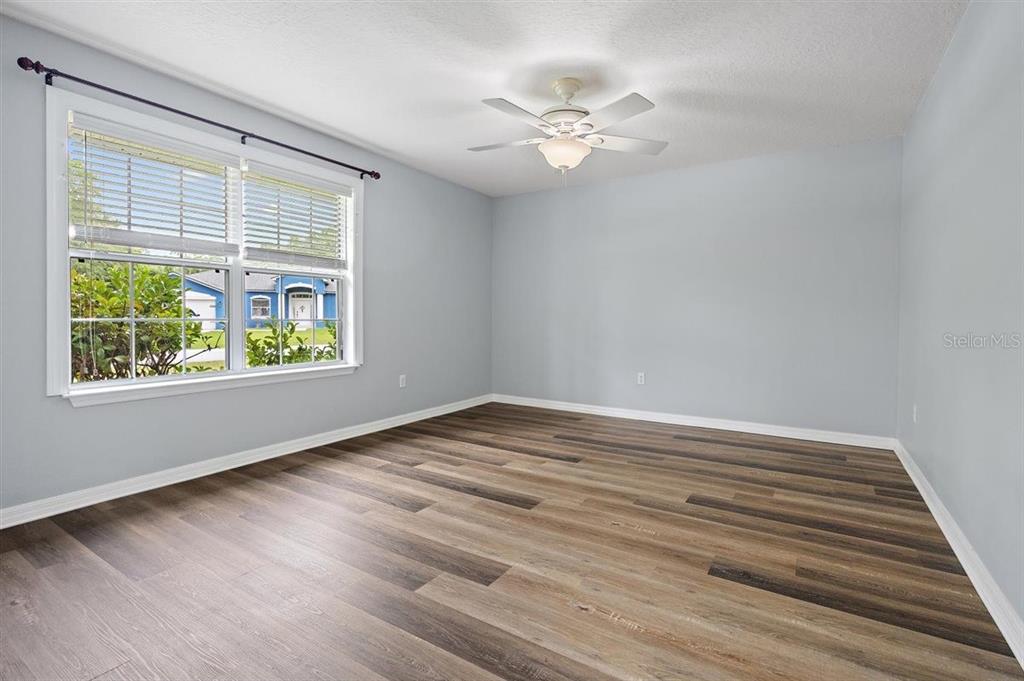 An empty bedroom features light gray walls, wood-look flooring, a ceiling fan, and a window — 54 SELMA TRAIL, PALM COAST, FL