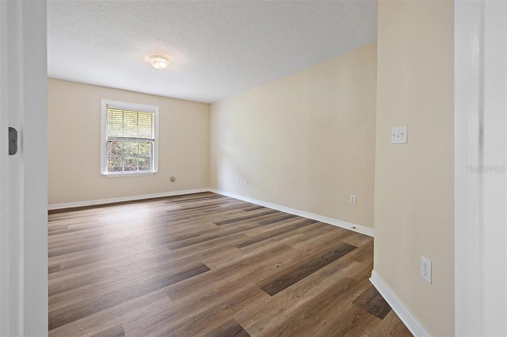An empty bedroom features light-colored walls, a single window, and wood-look vinyl plank flooring — 54 SELMA TRAIL, PALM COAST, FL