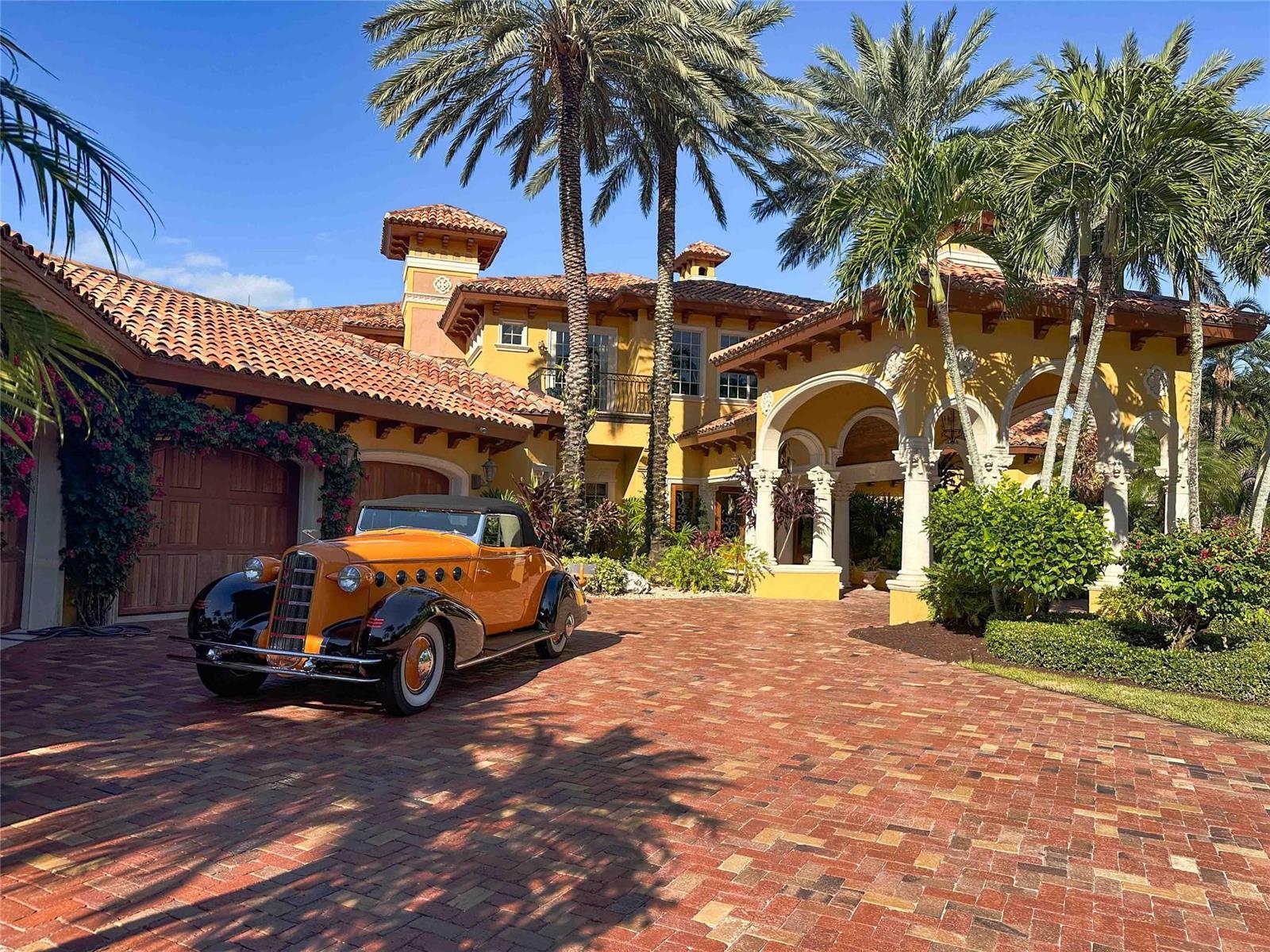 A vintage orange and black convertible is parked on a brick driveway before a Mediterranean-style home — 4089 SE Old Saint Lucie Boulevard, Stuart FL 34996, STUART, FL