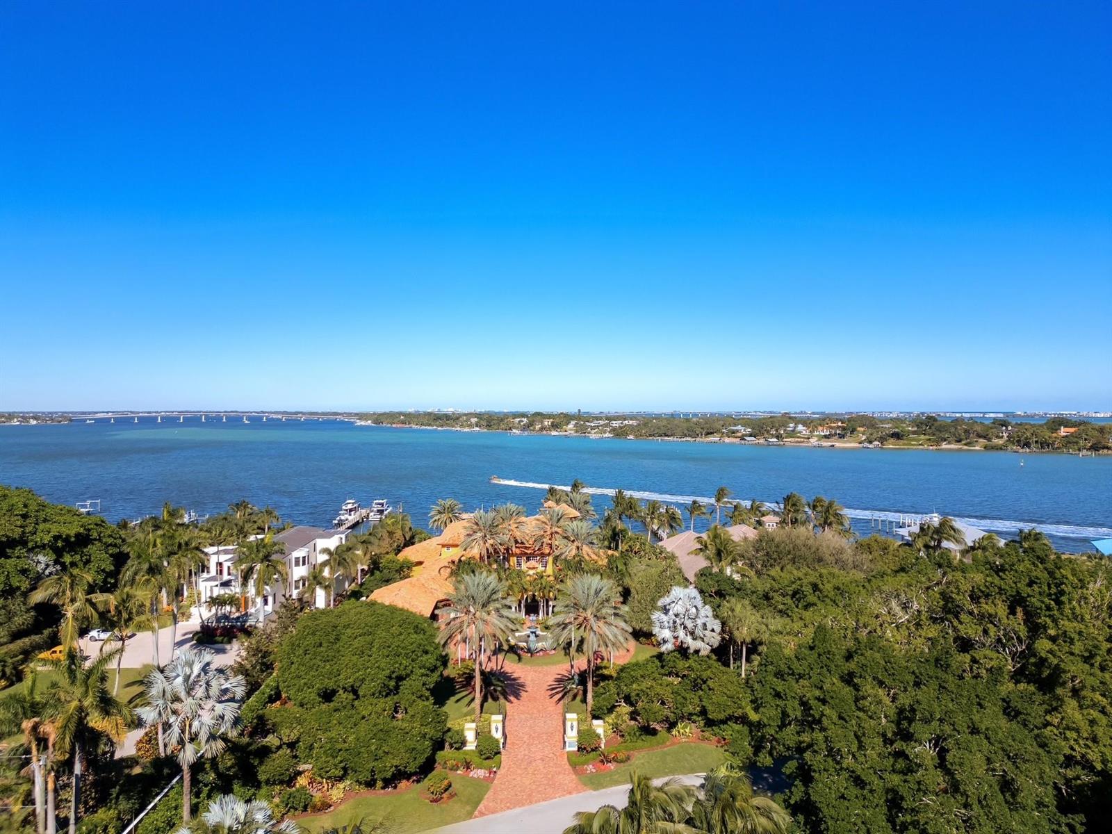 An aerial view of a waterfront estate featuring a brick driveway, lush landscaping, and boats — 4089 SE Old Saint Lucie Boulevard, Stuart FL 34996, STUART, FL