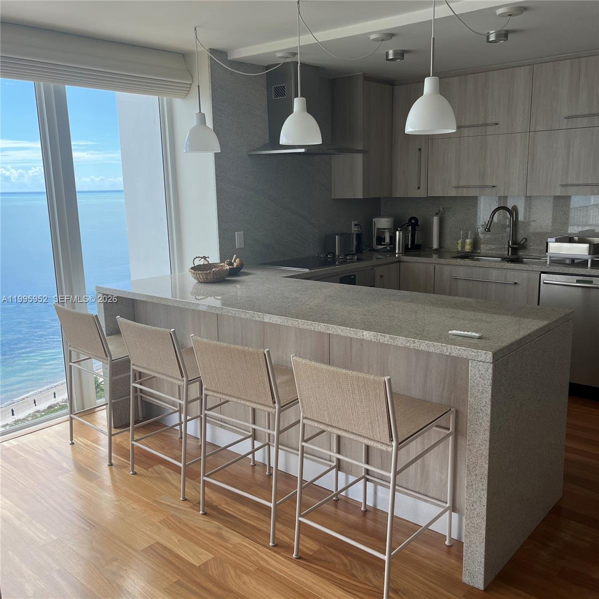 A kitchen with a granite breakfast bar, light wood cabinets, and a view of the ocean — 881 Ocean Dr # 18B, Key Biscayne FL 33149, KEY BISCAYNE, FL