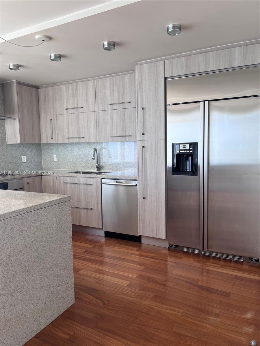 A modern kitchen features light wood cabinets, stainless steel appliances, and granite countertops — 881 Ocean Dr # 18B, Key Biscayne FL 33149, KEY BISCAYNE, FL