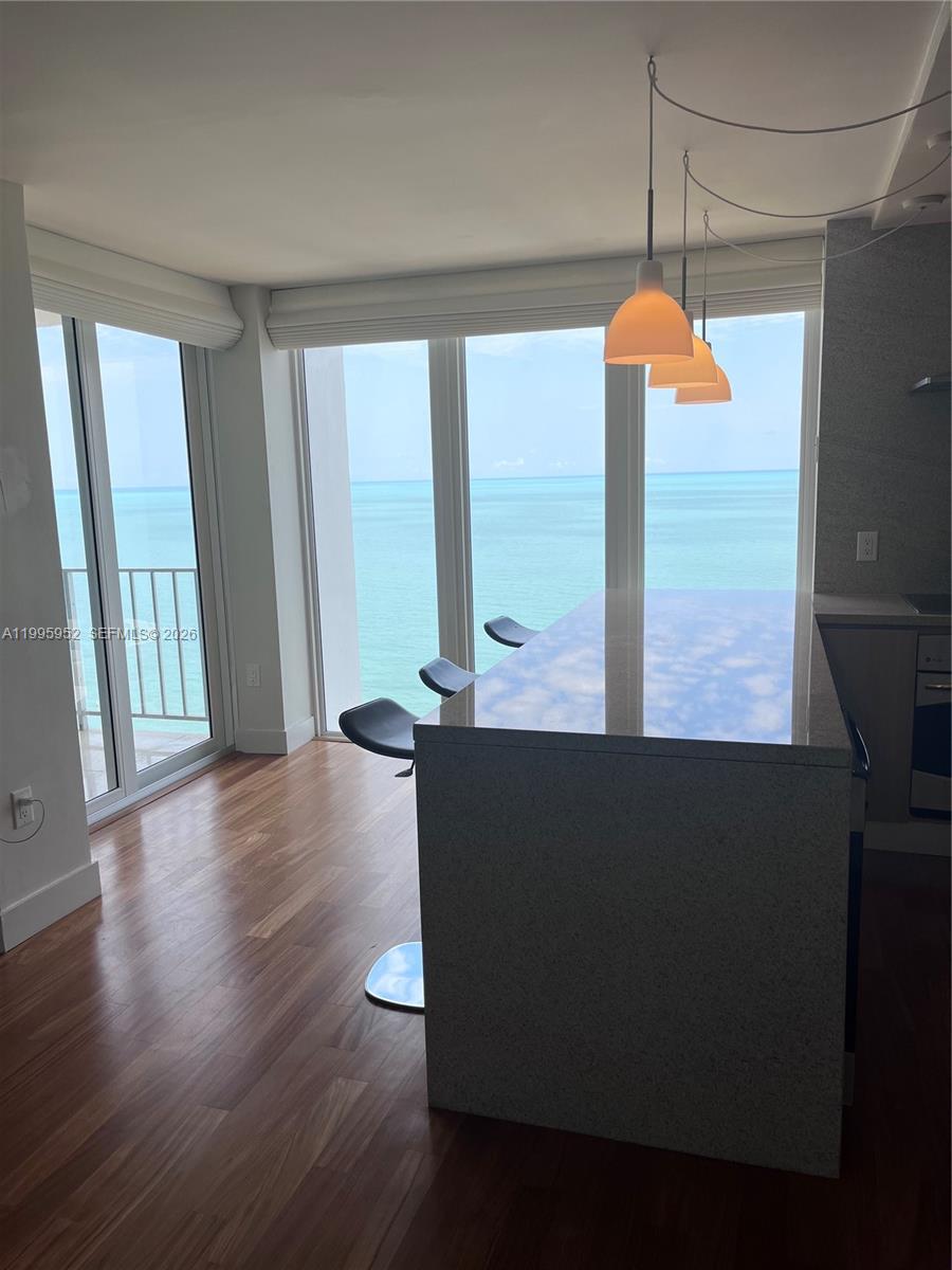 A kitchen island with bar stools sits in front of floor-to-ceiling windows overlooking the ocean — 881 Ocean Dr # 18B, Key Biscayne FL 33149, KEY BISCAYNE, FL
