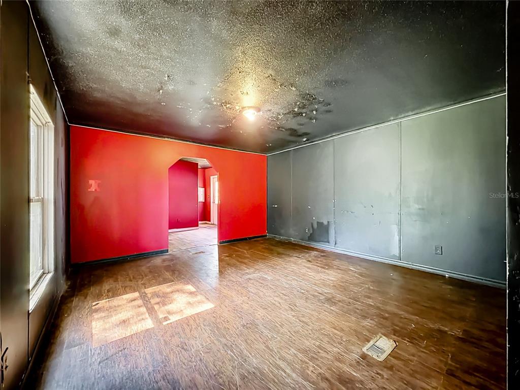 A room with dark wood flooring, red and gray walls, and a damaged black ceiling — 21420 NE 41ST STREET, WILLISTON, FL