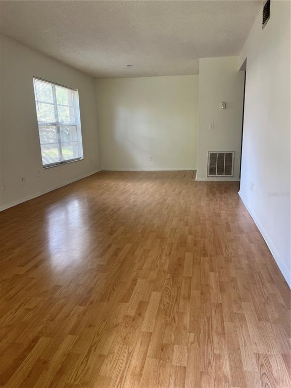 An empty room features light wood-look flooring, white walls, and a window with blinds — 14308 HANGING MOSS CIRCLE UNIT 102, TAMPA, FL