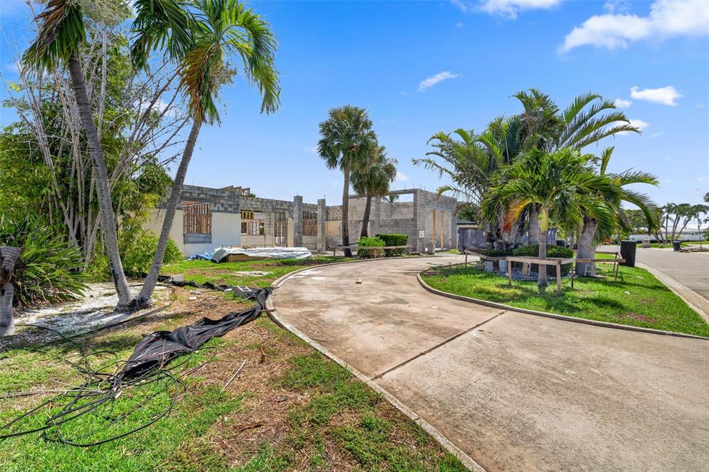 A construction site features concrete block walls and a curved concrete driveway under palm trees — 246 BAYSIDE DRIVE, CLEARWATER BEACH, FL