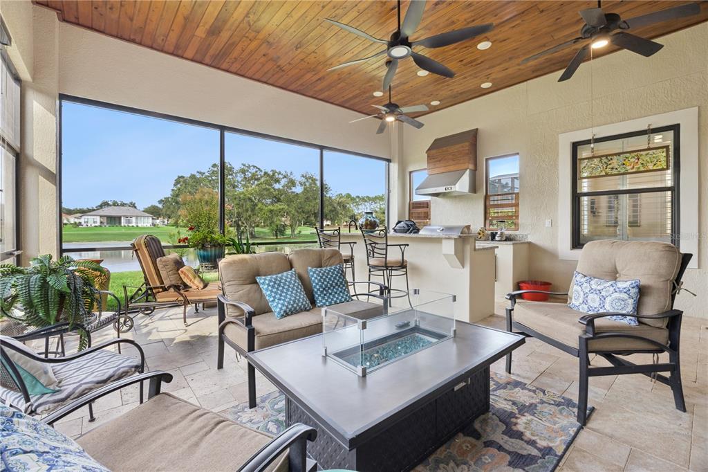 A screened-in patio features a fire pit, outdoor kitchen, and views of a golf course — 9219 SAN JOSE BOULEVARD, HOWEY IN THE HILLS, FL