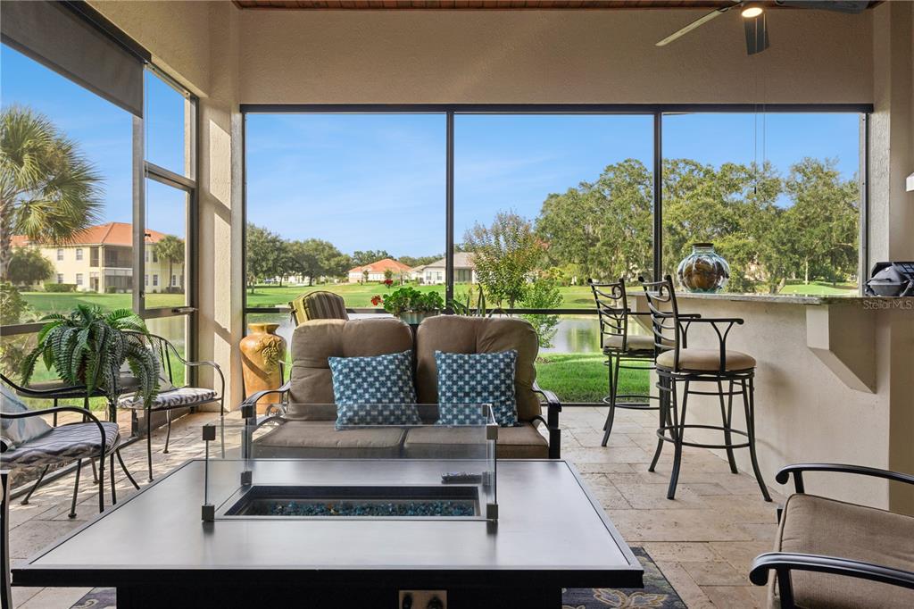 A screened-in patio features a fire pit, outdoor seating, and a view of a pond — 9219 SAN JOSE BOULEVARD, HOWEY IN THE HILLS, FL