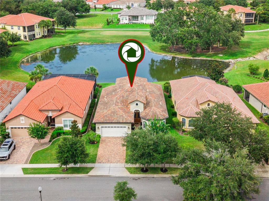 An aerial view of a suburban house with a tile roof situated beside a pond — 9219 SAN JOSE BOULEVARD, HOWEY IN THE HILLS, FL