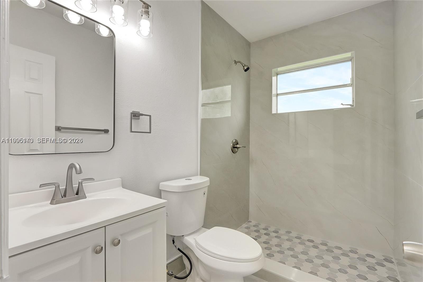 A bathroom features a white vanity, a toilet, and a walk-in shower with tiled walls — 1340 NW 102nd St, Miami FL 33147, MIAMI, FL