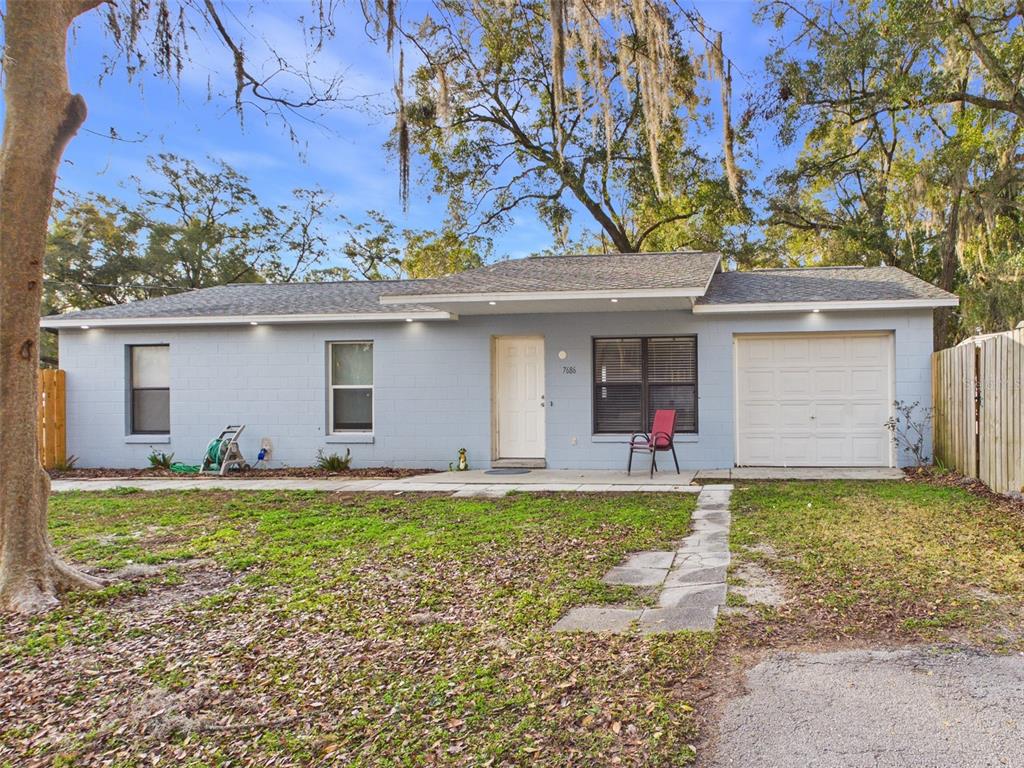 A single-story light blue house with a garage, a front door, and a paved walkway — 7686 SW 81ST STREET, OCALA, FL