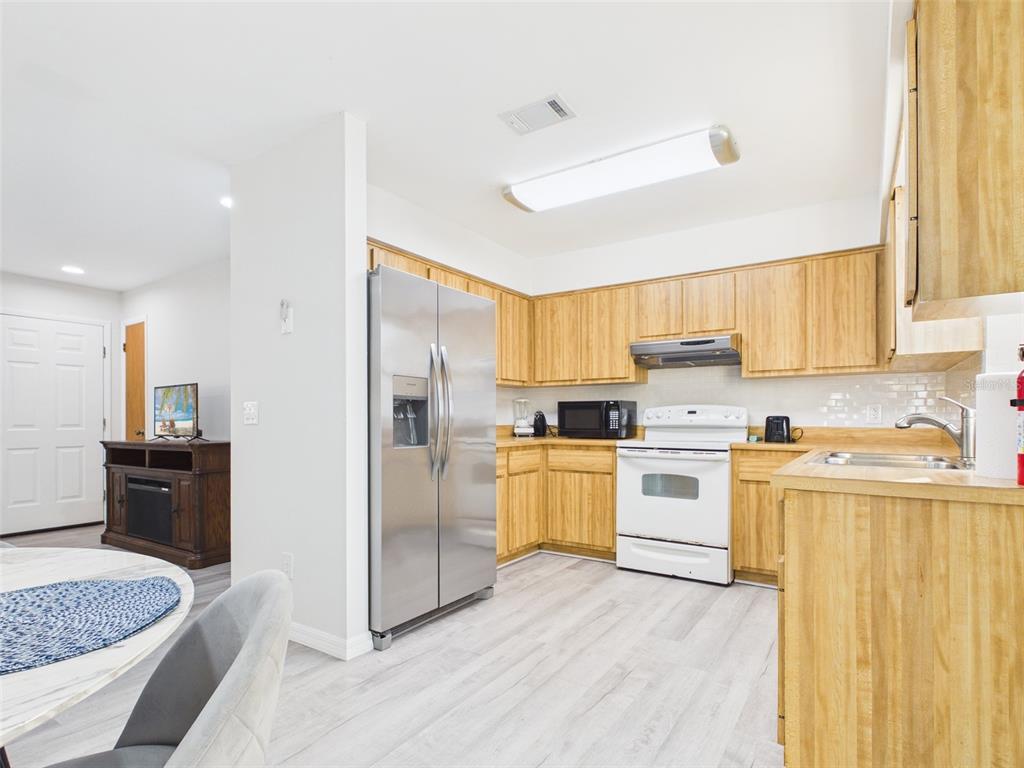 A kitchen features light wood cabinets, stainless steel appliances, and white walls — 7686 SW 81ST STREET, OCALA, FL