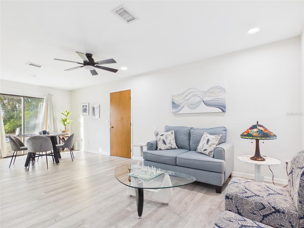 A living room features light wood-look flooring, a blue sofa, and a glass coffee table — 7686 SW 81ST STREET, OCALA, FL