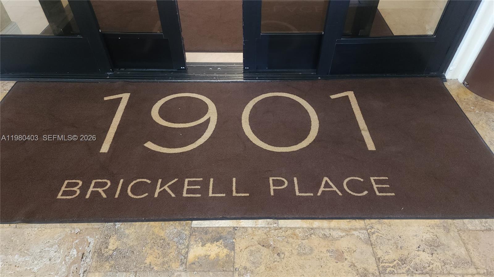 A brown floor mat with the text 1901 BRICKELL PLACE sits before glass entrance doors — 1901 Brickell Ave # B1407, Miami FL 33129, MIAMI, FL