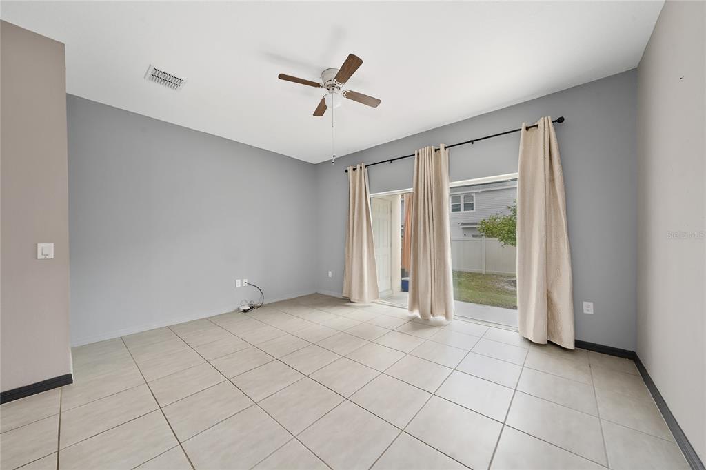 A room with light gray walls, large floor tiles, a ceiling fan, and sliding glass doors — 2060 VIEWFINDER STREET, KISSIMMEE, FL