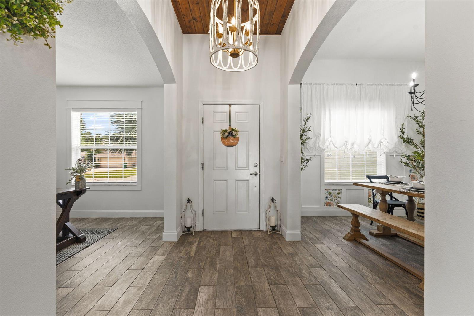 An entryway features wood-look tile flooring, a wood-paneled ceiling, and a white front door — 2141 SW Leafy Road, FL 34953, FL