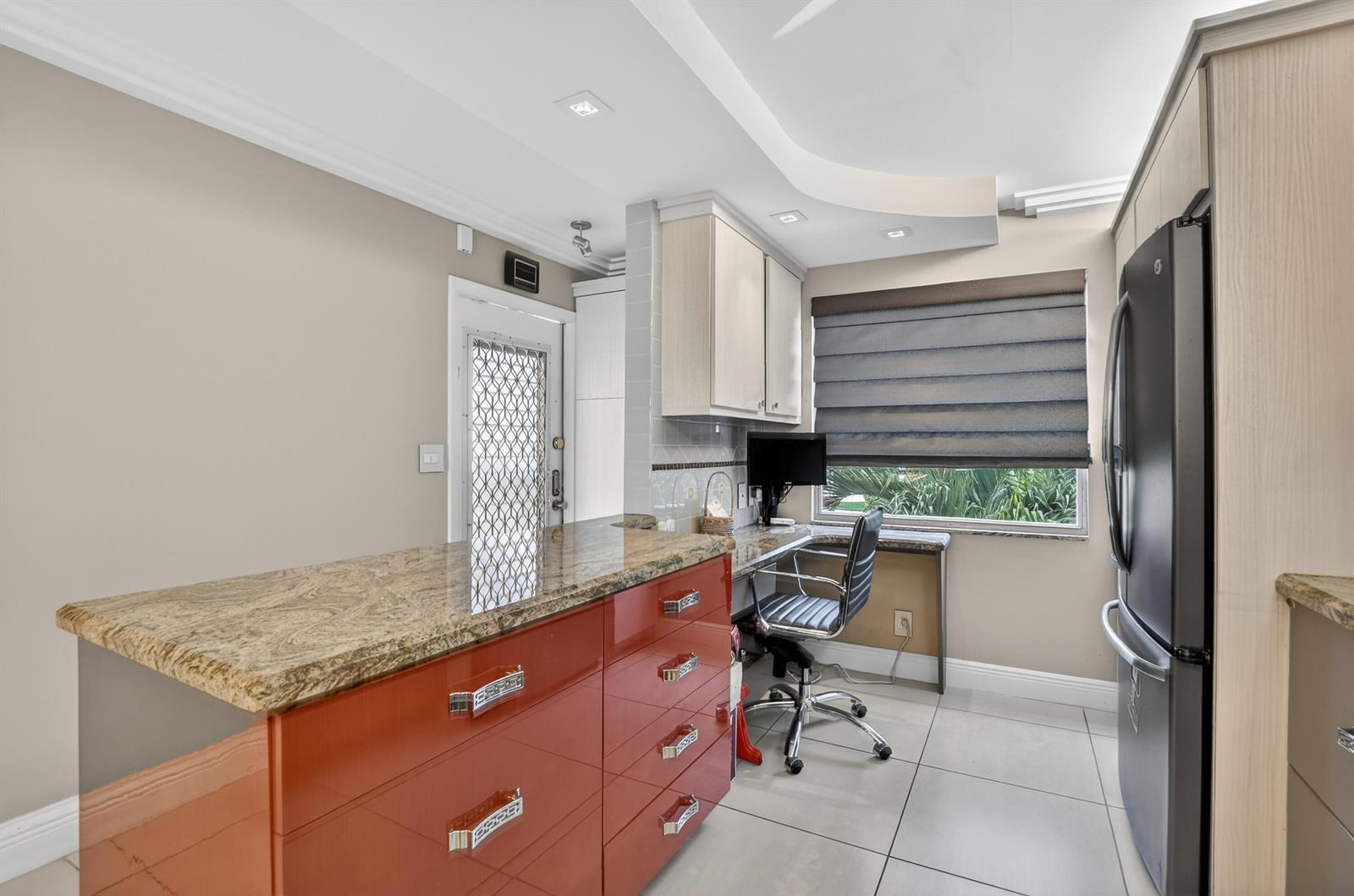 A kitchen features a red island with a granite countertop, a desk area, and a refrigerator — 3080 Yarmouth D, Boca Raton FL 33434, BOCA RATON, FL