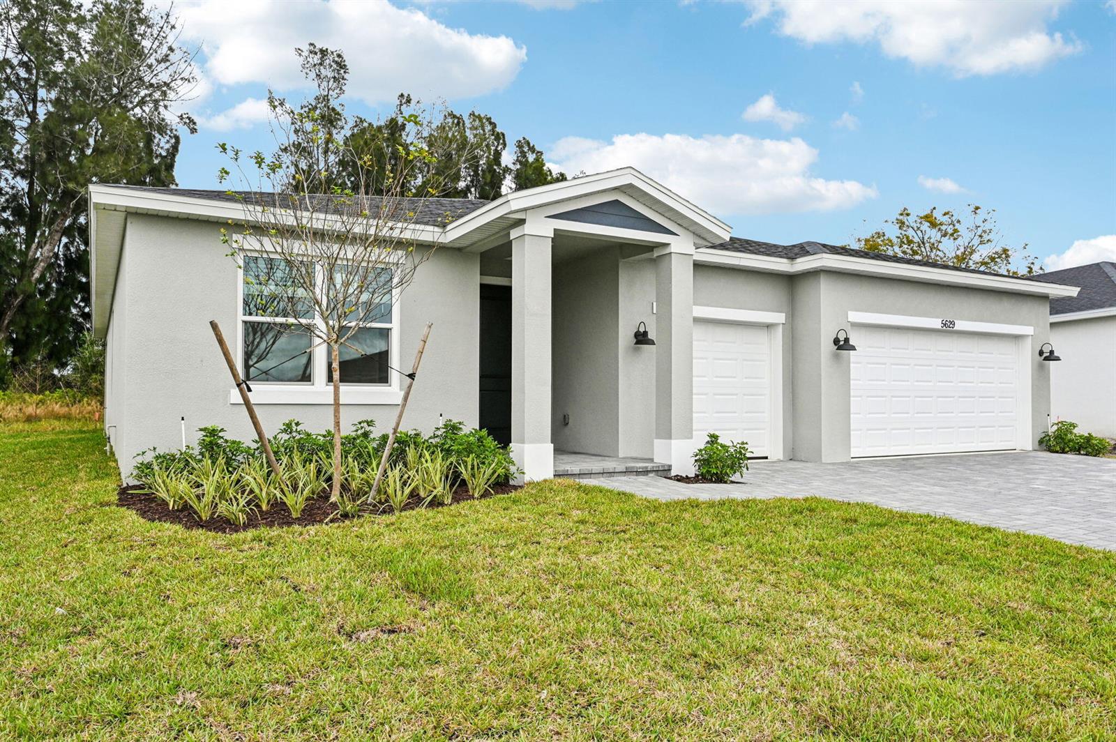 A single-story house with a gray stucco exterior, a two-car garage, and a paved driveway — 5629 Hampton Park Circle, Vero Beach FL 32966, VERO BEACH, FL