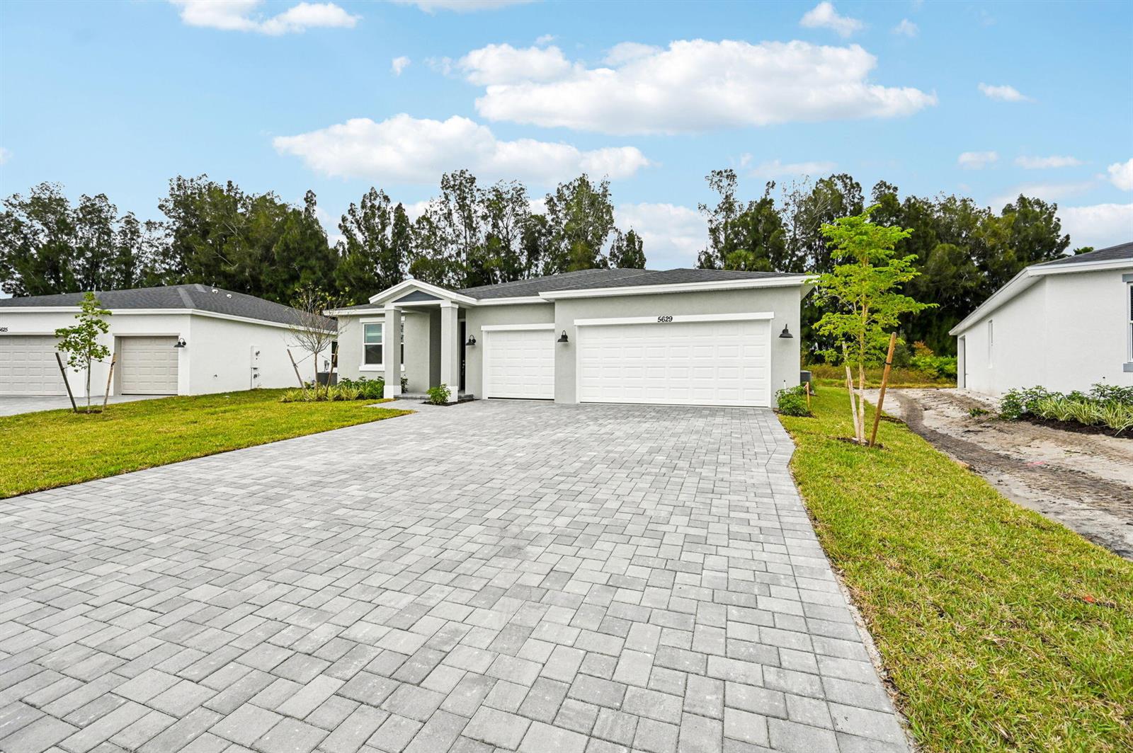 A single-story house with a paved driveway, three-car garage, and light gray exterior siding — 5629 Hampton Park Circle, Vero Beach FL 32966, VERO BEACH, FL