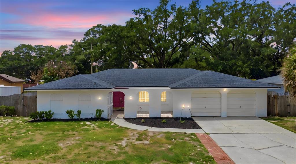 A single-story white house with a dark roof, two-car garage, and a magenta front door — 6785 TAMARIND CIRCLE, ORLANDO, FL