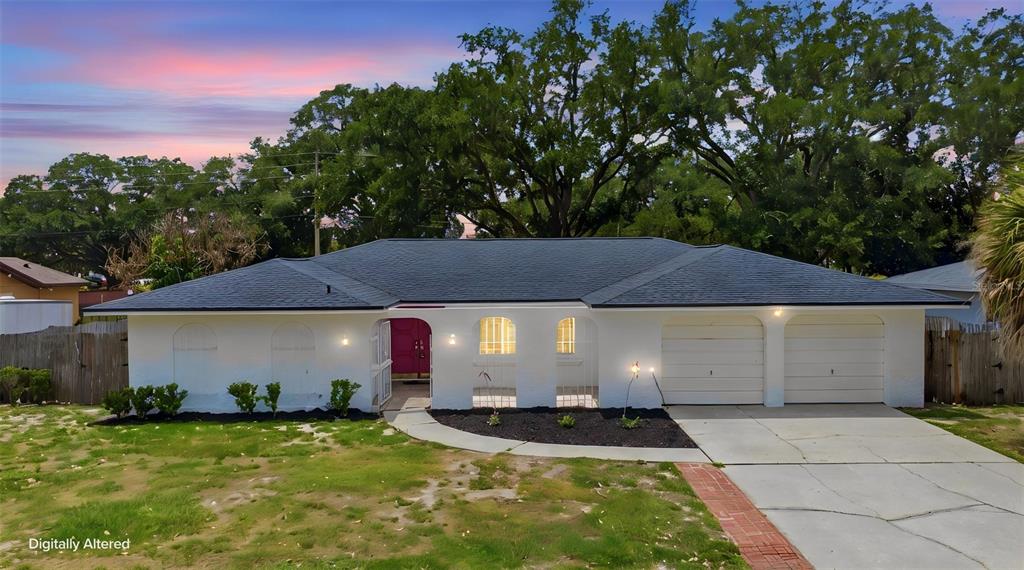A single-story white house with a dark roof, two garage doors, and a front walkway — 6785 TAMARIND CIRCLE, ORLANDO, FL