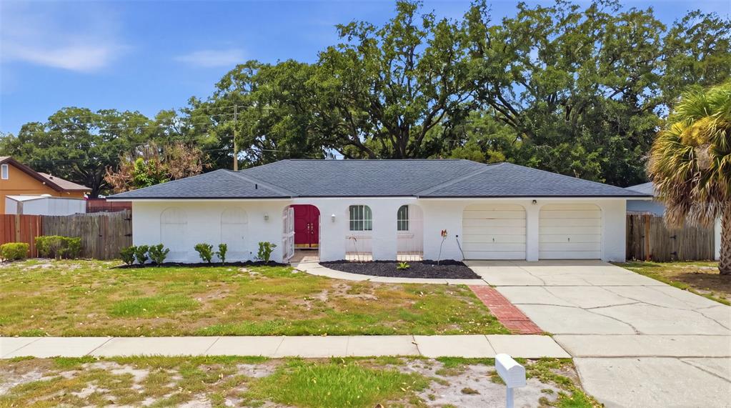 A single-story white house with a dark roof, two-car garage, and a front courtyard — 6785 TAMARIND CIRCLE, ORLANDO, FL