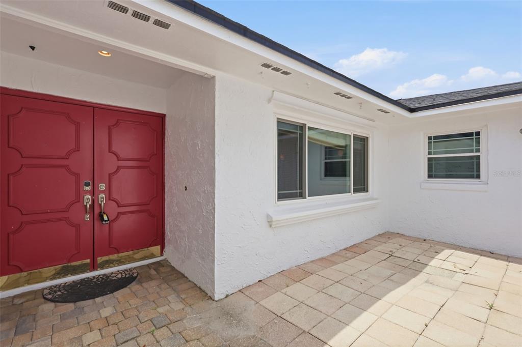 A white house exterior features a red double front door and a paved patio area — 6785 TAMARIND CIRCLE, ORLANDO, FL