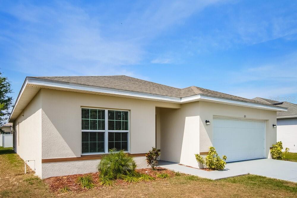 A single-story house with a beige stucco exterior, a two-car garage, and a shingled roof — 651 MERCADO COURT, KISSIMMEE, FL