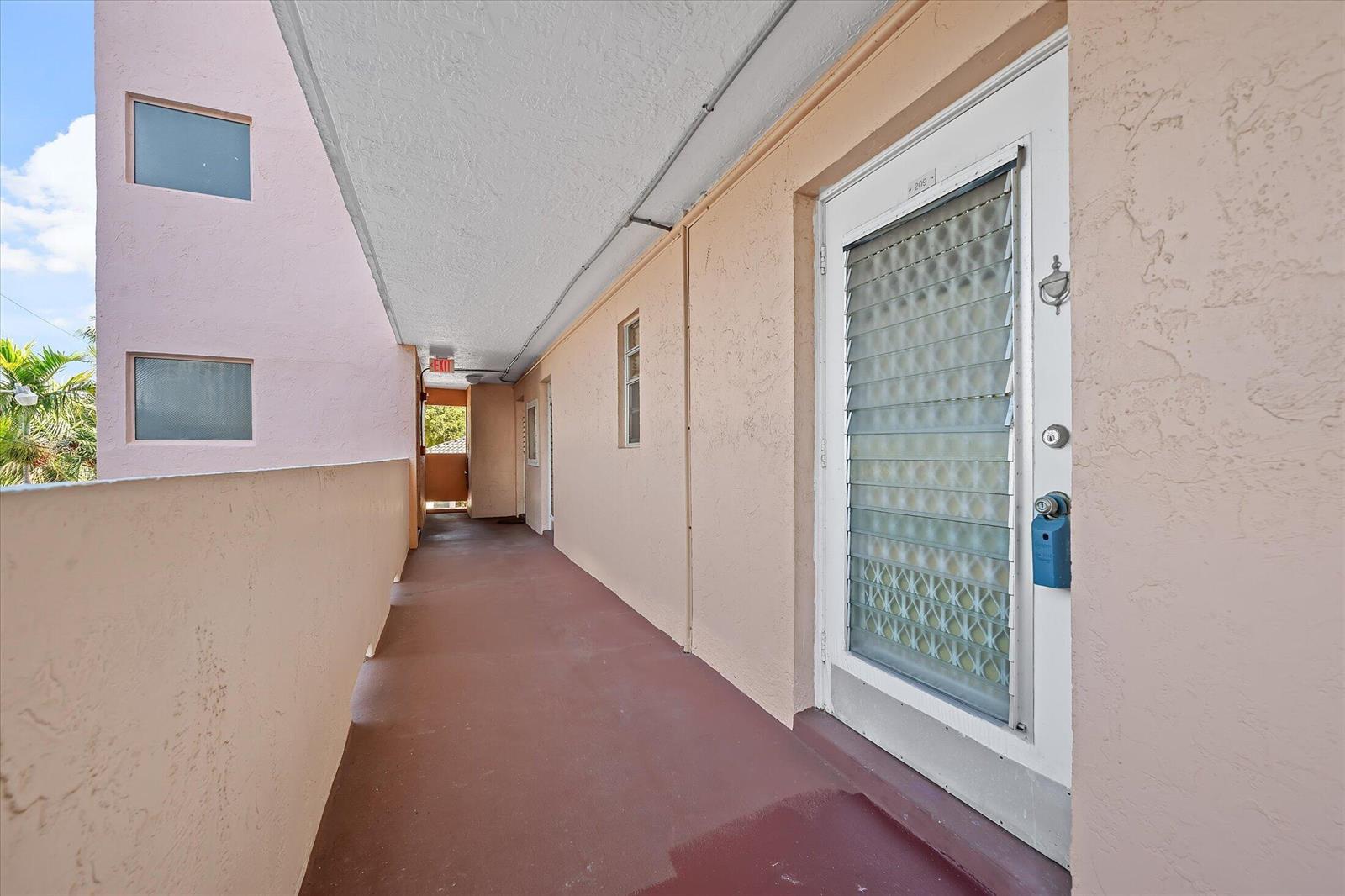 An exterior walkway leads to a door labeled 209 with a louvered glass storm door — 3201 NE 14th Street Causeway # 209, Pompano Beach FL 33062, POMPANO BEACH, FL
