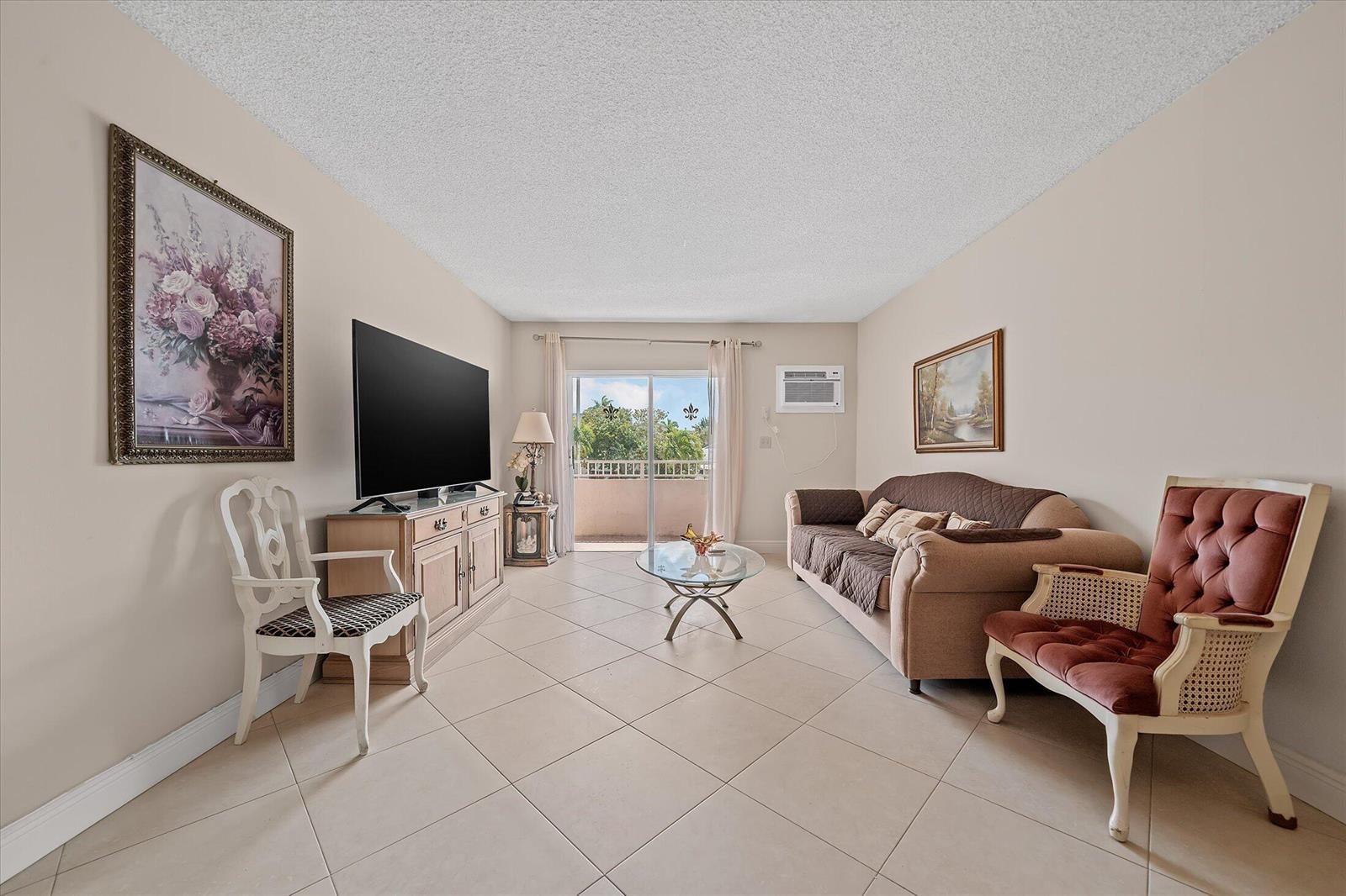A living room features tiled floors, a sofa, two accent chairs, and a sliding glass door — 3201 NE 14th Street Causeway # 209, Pompano Beach FL 33062, POMPANO BEACH, FL