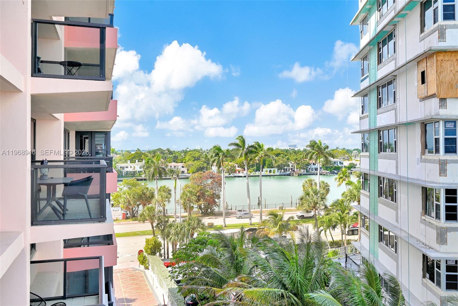 A balcony view overlooks a swimming pool, palm trees, and the ocean next to a building — 5225 Collins Ave # 714, Miami Beach FL 33140, MIAMI BEACH, FL