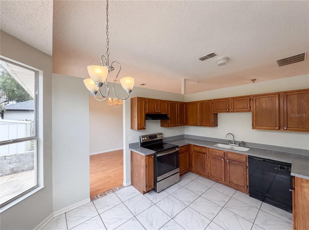 A kitchen features wood cabinets, stainless steel appliances, gray countertops, and white tile flooring — 5263 CLARION OAKS DRIVE, ORLANDO, FL
