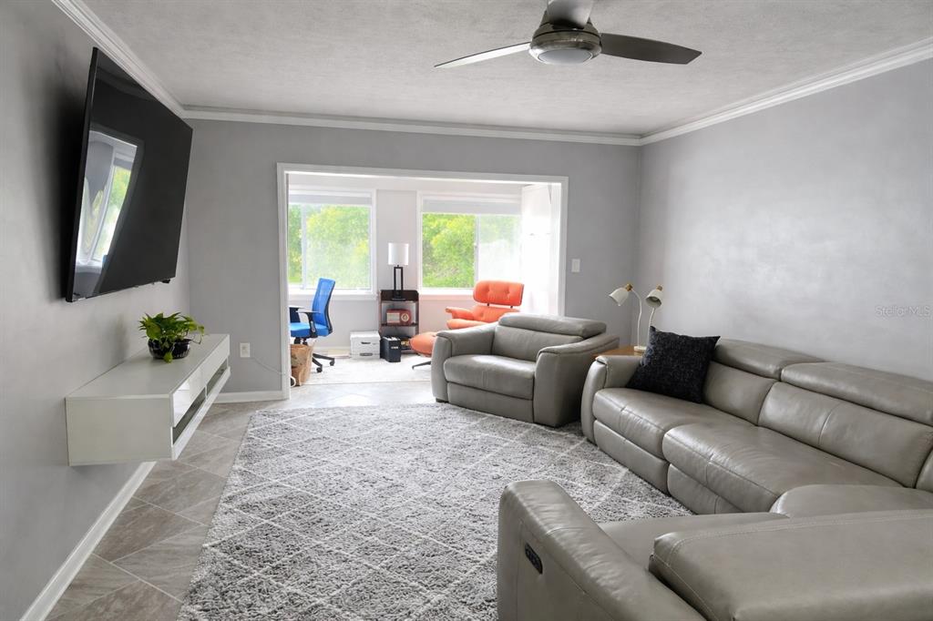 A living room features gray walls, a large sectional sofa, a floating console, and tile flooring — 8651 10TH STREET N UNIT 228, ST PETERSBURG, FL